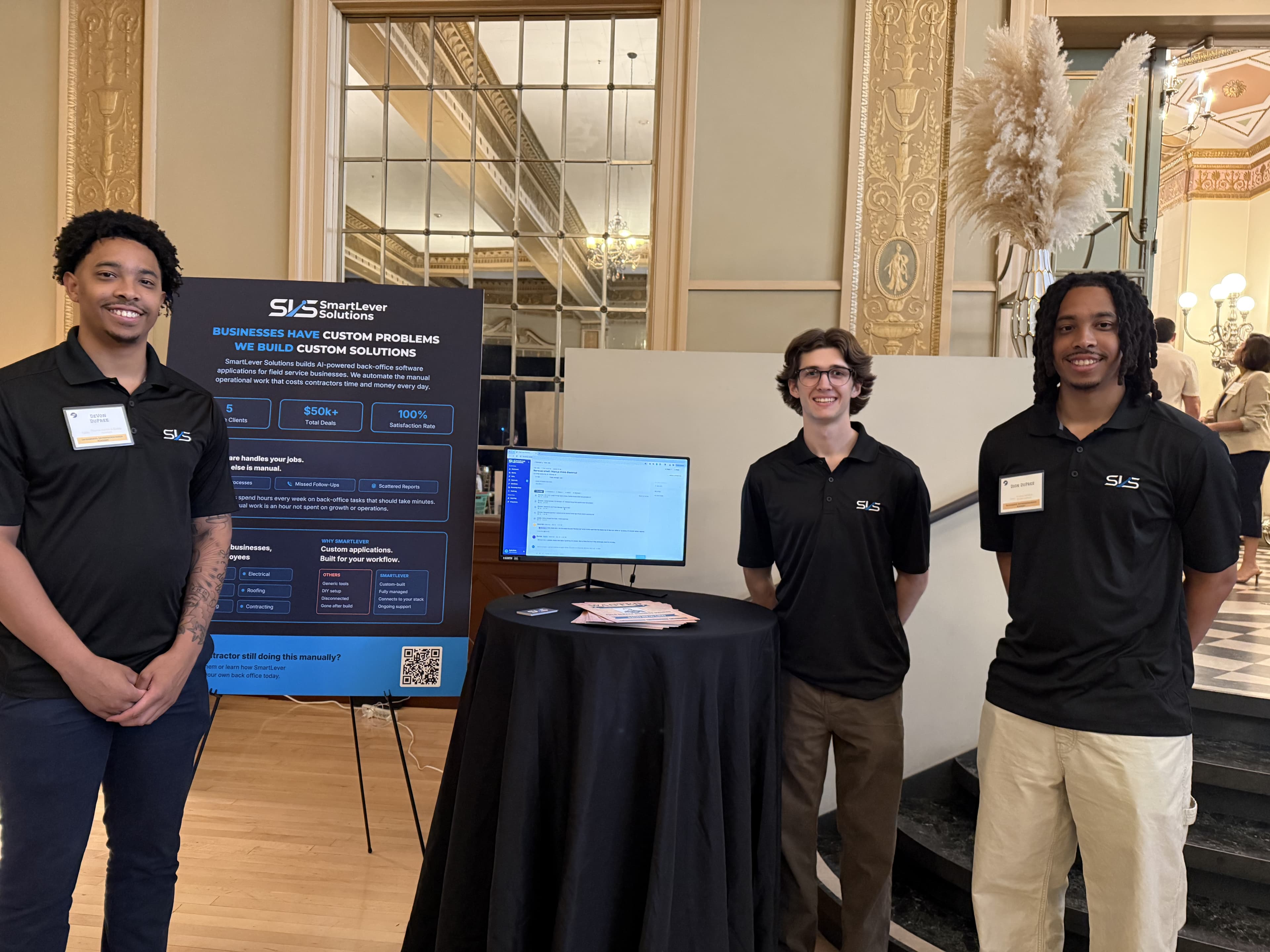 Left to right: DeVon DuPree, Jacob Squires, and Dion DuPree at the SmartLever Solutions booth during the 2026 Sacramento Entrepreneurship Academy showcase, beside a poster and a monitor running the platform